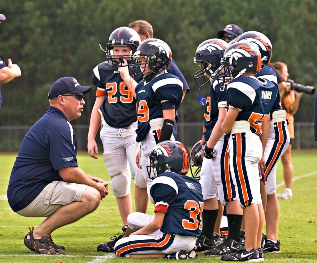 A coach talking to the players on a Youth football team about their cookbook fundraiser