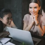 Women's club meeting around a computer to discuss their successful cookbook fundraiser